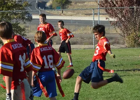 OCS student kicking a football on athletic field