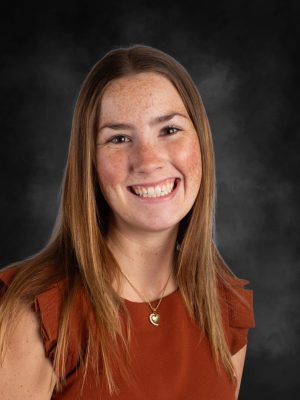 Portrait of Mrs. Sierra Lasagna smiling with auburn hair and freckles.