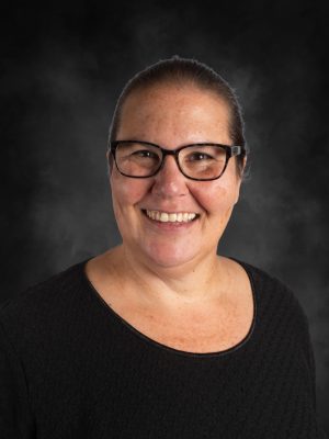 Ms. Lisa Long, smiling woman with glasses in a black top against a dark background.