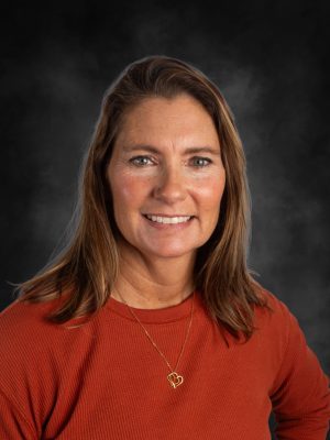 Mrs. Sara Poblano portrait with auburn hair and a warm smile.