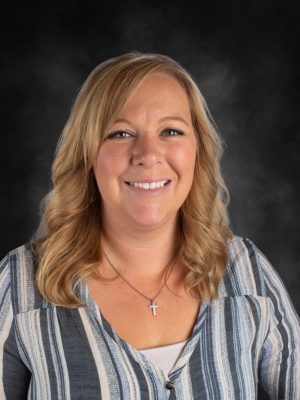 Timber Stanton portrait. Blonde woman with a cross necklace smiles at the camera.