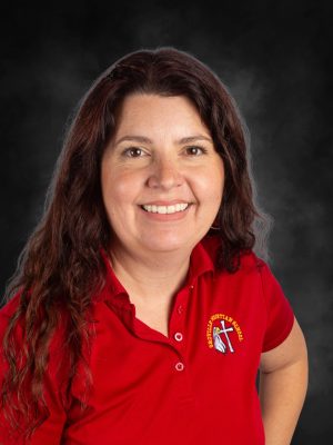 Mrs. Rochelle Griffiths, wearing a red shirt with the school logo, smiles warmly.